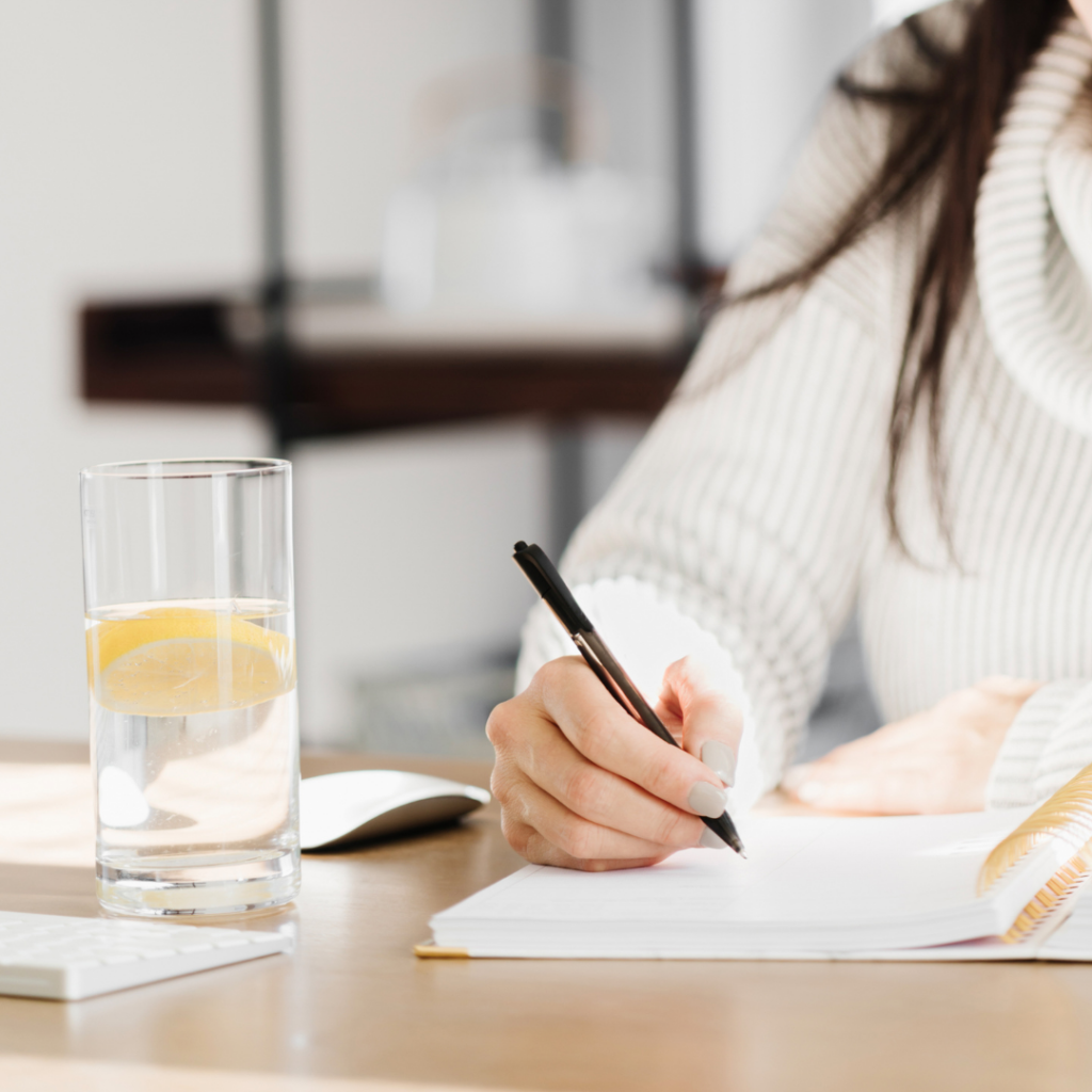 Woman writing on her notebook with while drinking lemon juice